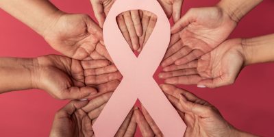 Women against breast cancer. Cropped image of woman holding a pink paper ribbon, on red background