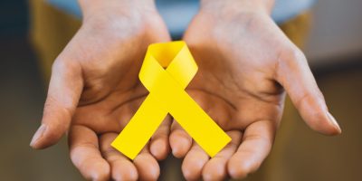 girl-hands-holding-yellow-ribbon-childhood-cancer-2025-01-10-12-41-09-utc