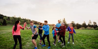 A large group of fit and active people resting after doing exercise in nature.